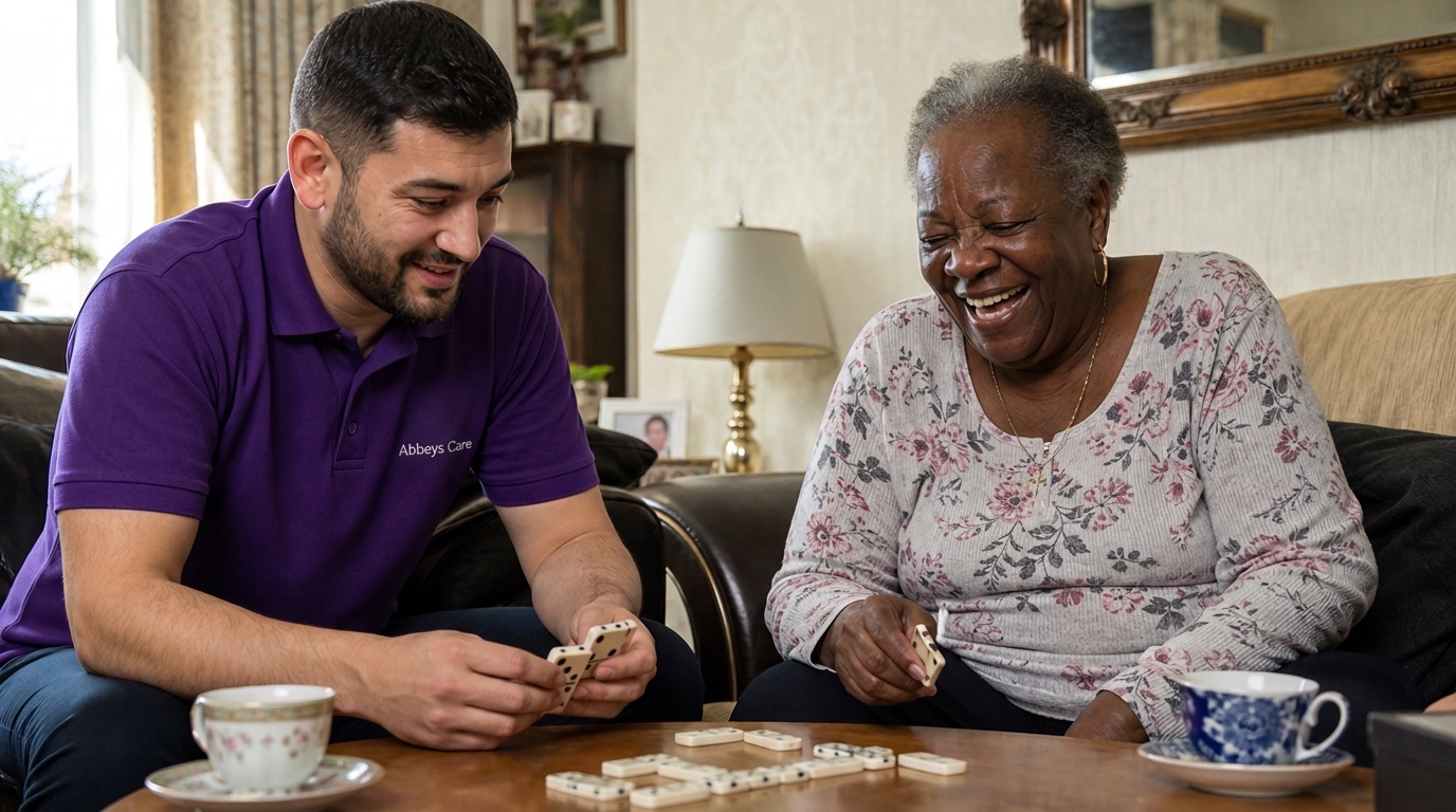 Abbeys Care carer in purple branded uniform sharing a game of dominoes with an elderly man during a home care visit in East London